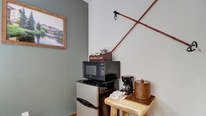 A kitchenette with a microwave, refrigerator, coffee maker, and a small wooden table.