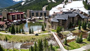A lodge with multiple buildings, a lake, and a mountain backdrop.