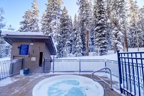 A wooden deck with a hot tub surrounded by snow-covered trees. - Ten Mile Haus A-6 2br 2ba 2 Bedroom Condo (Copper Mountain)