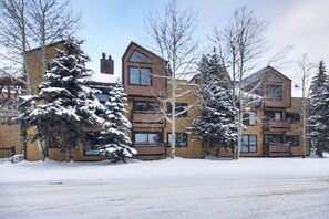 Stunning multi-story building with brick and wood accents, featuring large windows with shutters.