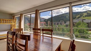 Un comedor con mesa y sillas de madera, ventanas amplias con vista a la montaña.