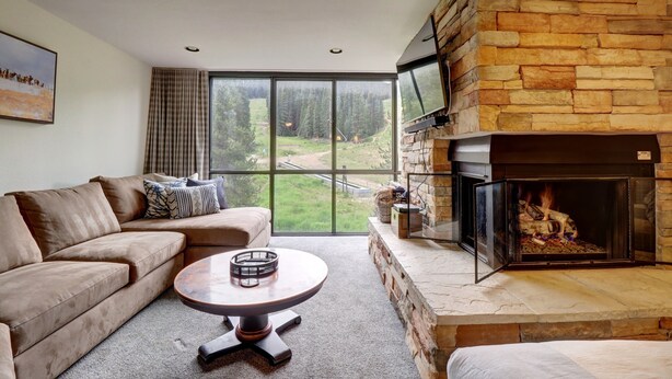A living room with a stone fireplace, a large window, a sofa, and a coffee table.