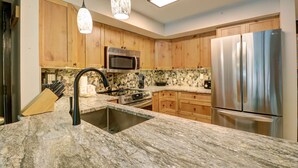 A kitchen with wooden cabinets, a stainless steel refrigerator, a microwave, and a granite countertop. - Mp615 Mountain Plaza Center Village Condo 2br 3ba Hot Tub 2 Bedroom Condo (Copper Mountain)