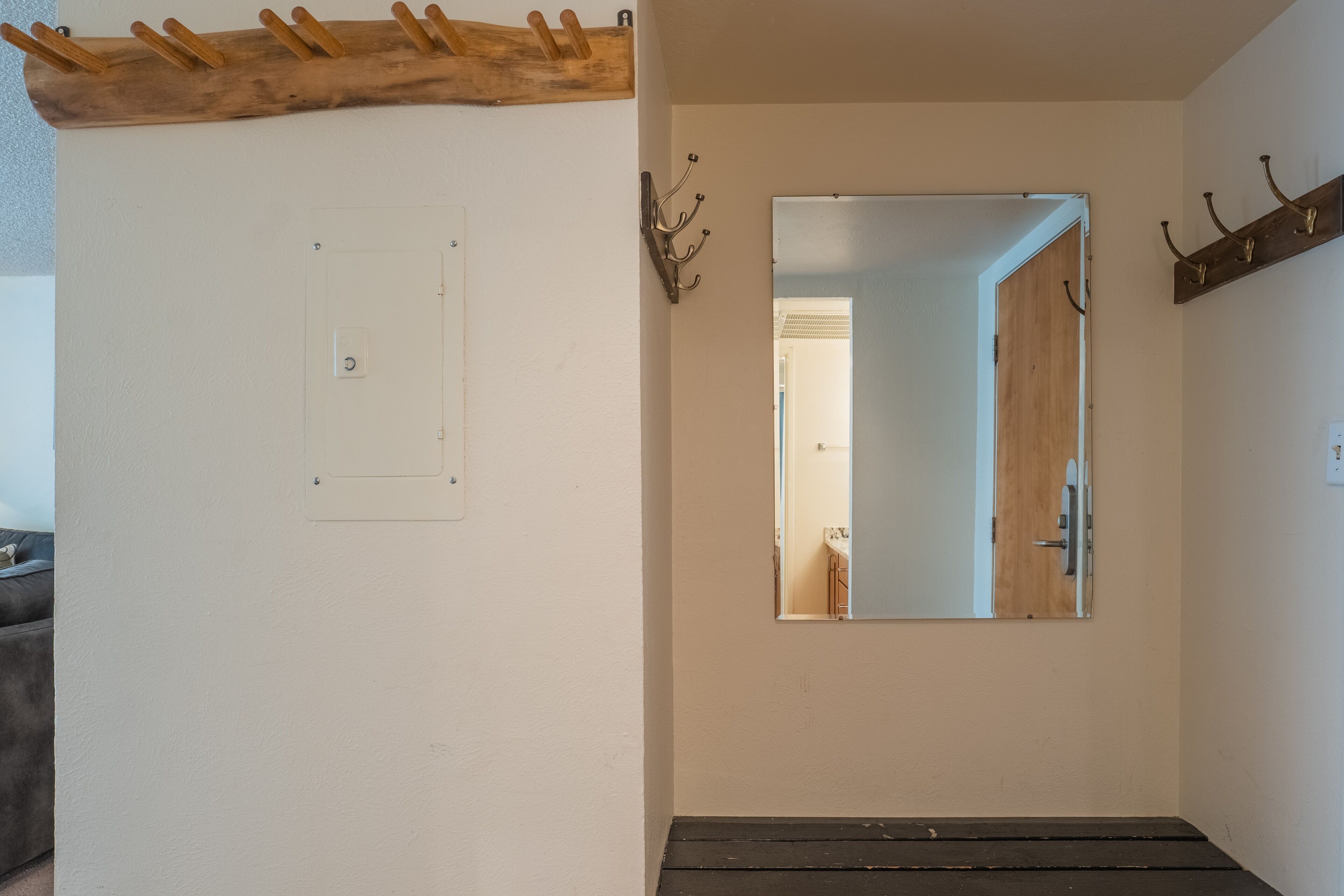 A hallway with a wooden bench, a coat rack, a mirror, and a door.