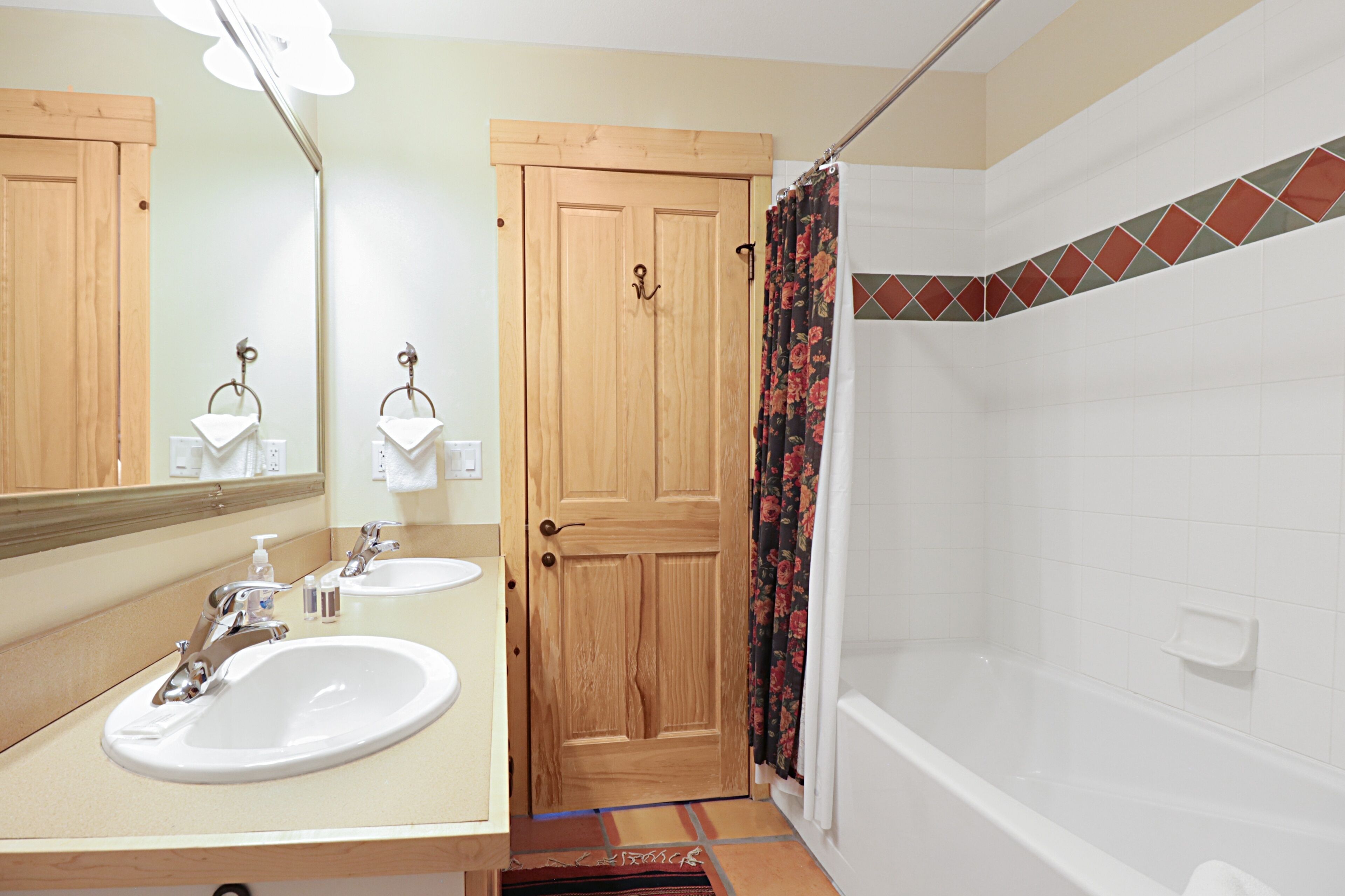 A bathroom with two sinks, a shower, and a wooden door.