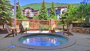 A pool area with Adirondack chairs, a sign with spa rules, and a mountain backdrop. - Tx314 Taylors Crossing 2 Bedroom Condo (Copper Mountain)