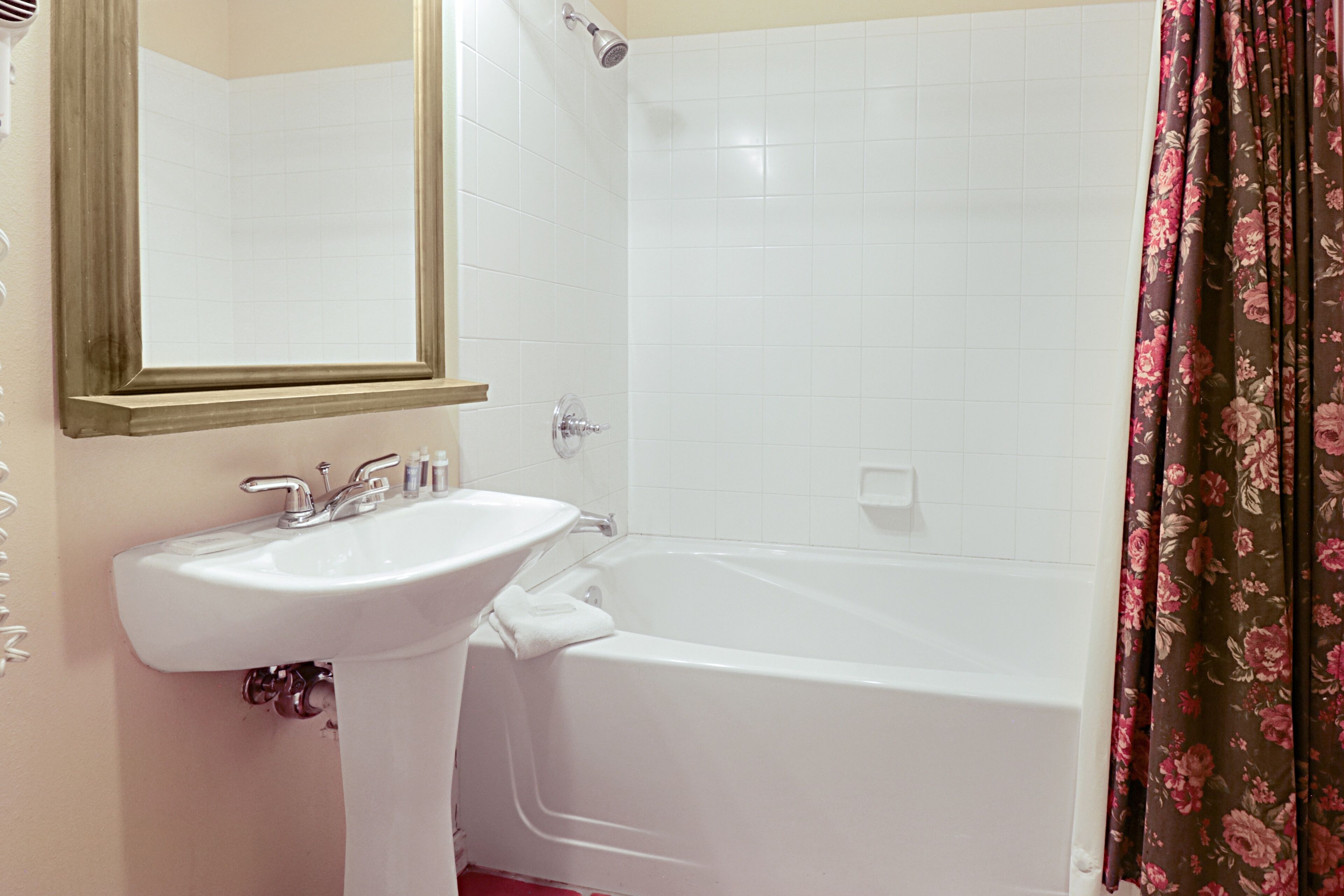 Une salle de bain avec un lavabo blanc, un miroir, une baignoire et un rideau de douche.
