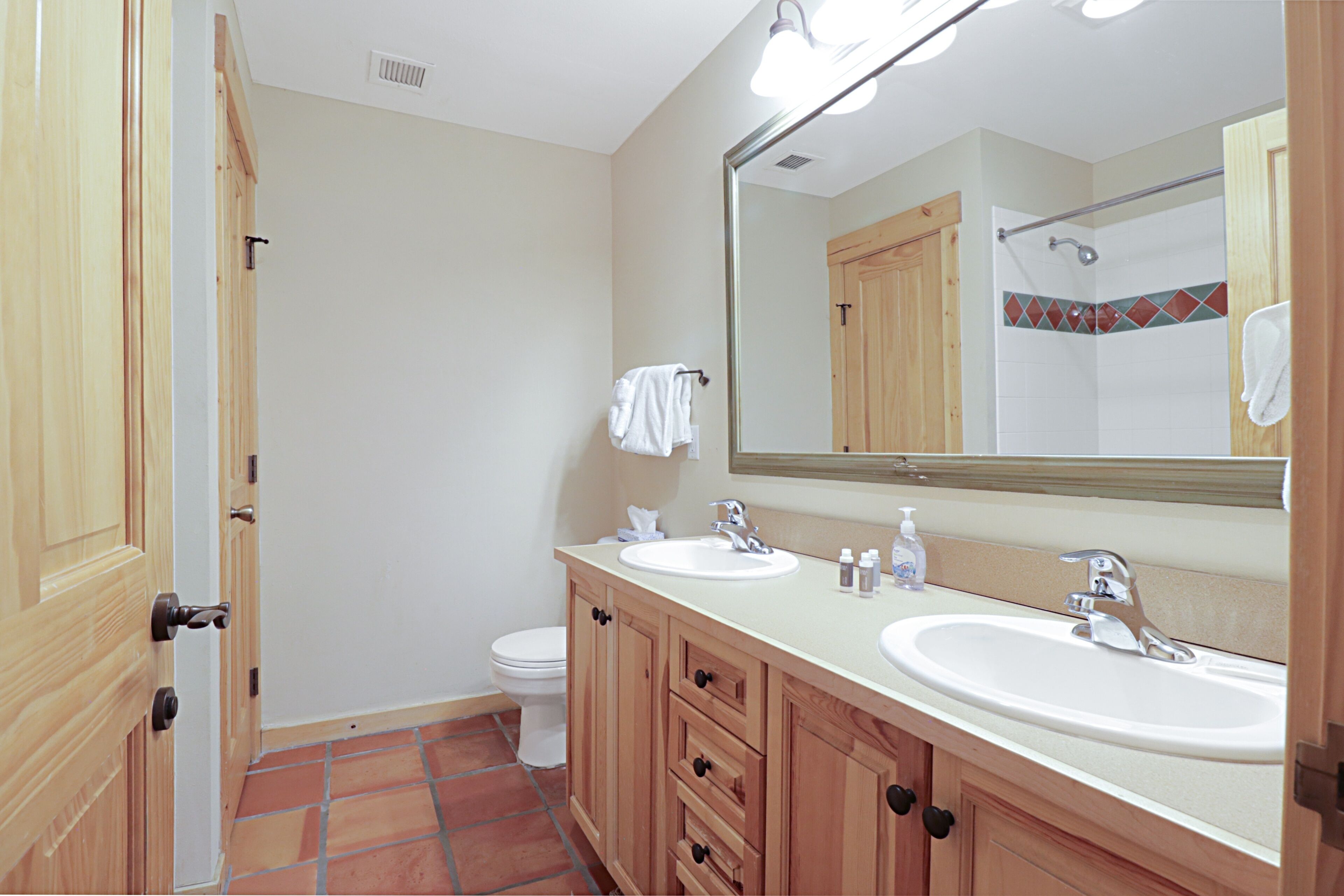 A bathroom with two sinks, a mirror, and a toilet.