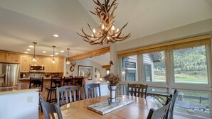 A spacious kitchen with wooden cabinets, a large dining table, and a chandelier.