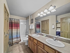 A bathroom with two sinks, a shower, and a large mirror.