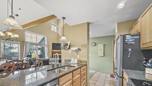 A modern kitchen with a central island, stainless steel appliances, wooden cabinets, and a large window providing natural light. - B6 Tarn Landing 1br + Loft, 3ba 1 Bedroom Condo (Frisco)
