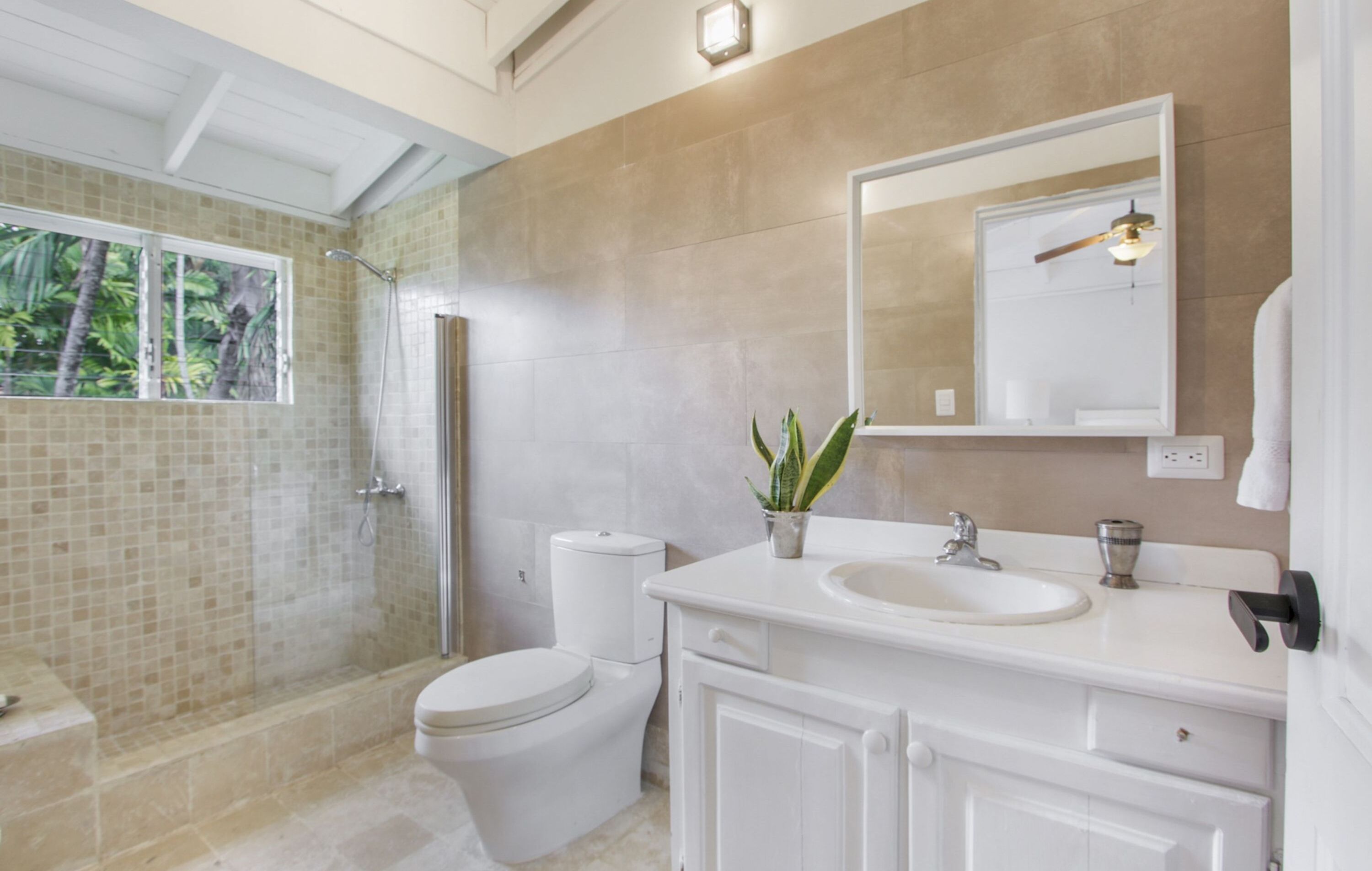Un baño moderno con ducha de vidrio, inodoro, lavamanos y espejo.