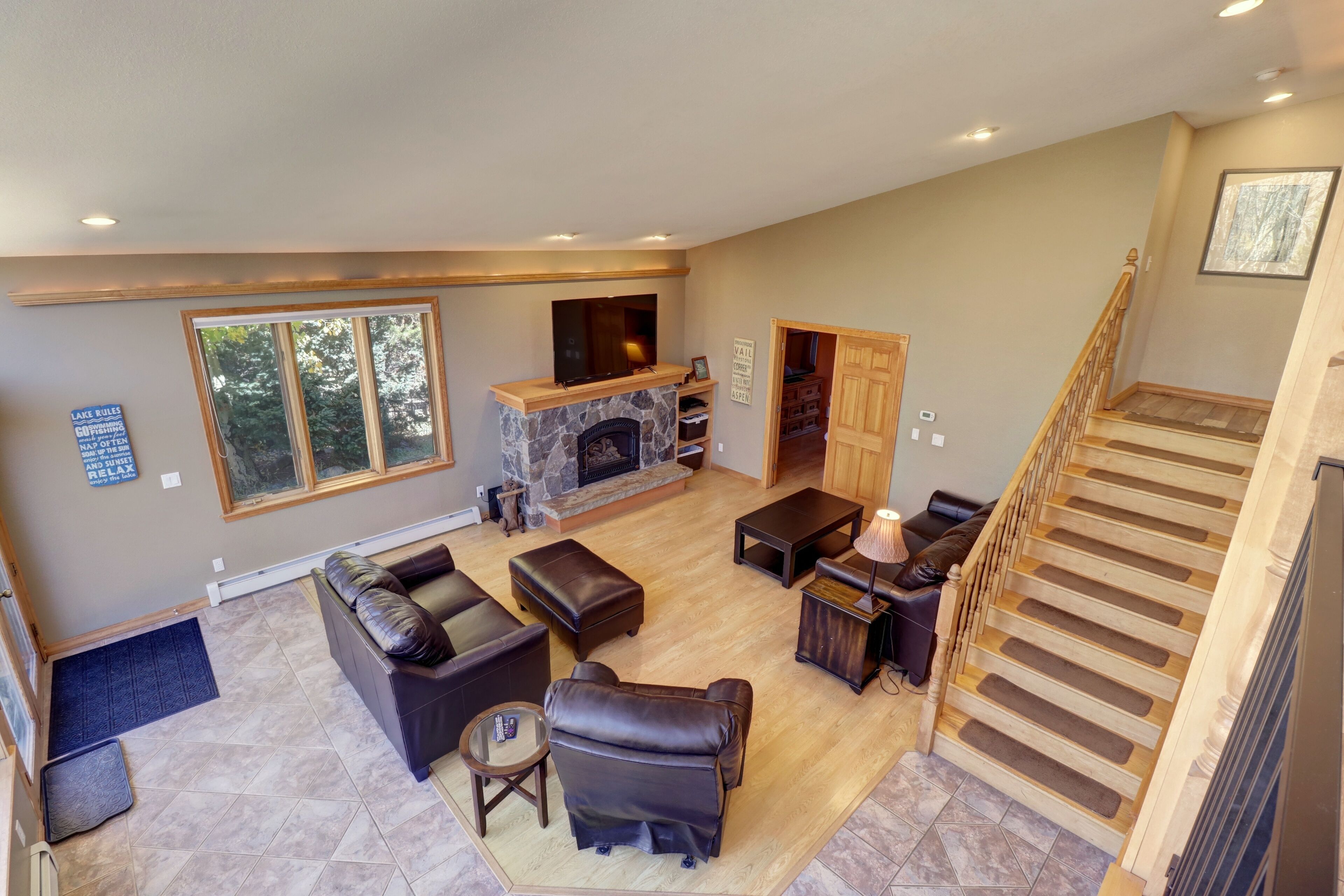 A spacious living room with a fireplace, leather furniture, and a staircase.
