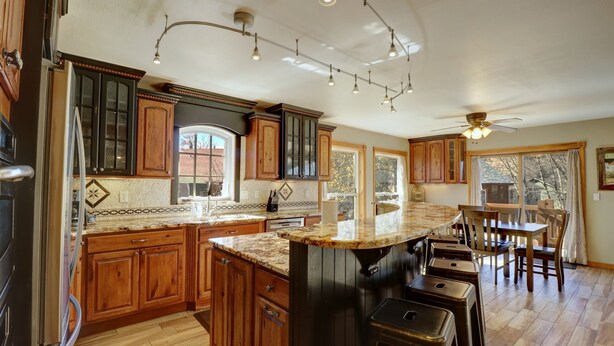 A kitchen with wooden cabinets, a marble countertop, and a bar area with stools. - 334 Willow Lake Ct. 4br W/loft 3ba 4 Bedroom Townhouse (Silverthorne)