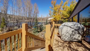 A wooden deck with a view of a lake and trees, a covered grill, and a wooden railing. - 334 Willow Lake Ct. 4br W/loft 3ba 4 Bedroom Townhouse (Silverthorne)