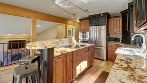 A modern kitchen with a large island, wooden cabinets, stainless steel appliances, and a stone countertop. - 334 Willow Lake Ct. 4br W/loft 3ba 4 Bedroom Townhouse (Silverthorne)