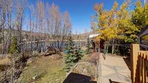 A view of a backyard with a wooden deck, a swing set, and a small pond. - 334 Willow Lake Ct. 4br W/loft 3ba 4 Bedroom Townhouse (Silverthorne)