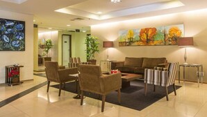 A modern lobby with a seating area, a large painting, and a reception desk. - Premium Suite No. 102 at the Metropolitan Hotel in Bauru, with magnificent breakfast (Jardim Estoril Bauru)