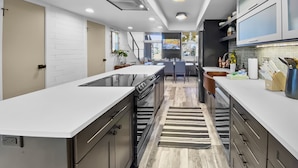 A modern kitchen with a central island, built-in appliances, and a dining area with a view of the outdoors.