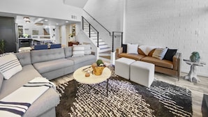 A modern living room with a sectional sofa, a coffee table, and a staircase leading to another level.