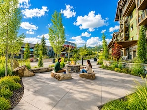 A courtyard with outdoor seating, a fire pit, and a view of buildings and trees. - 4202 Modern Vibe At Fairway Springs 3 Bedroom Home (Park City)