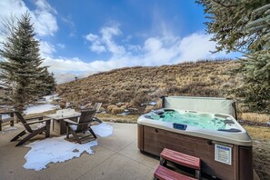 A hot tub with a safety sign, outdoor seating, and a view of a mountainous landscape. - 2744 The Cove! Modern Luxury Townhome With Hot Tub, Pool, And Shuttle To The Slopes! 4 Bedroom Home (Park City)