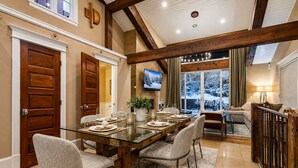 A dining area with a glass table, chairs, and a TV mounted on the wall. - 521 Woodside Gem True Ski-in Ski-out On The Gold Coast 3 Bedroom Home (Park City)