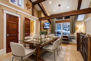 A dining area with a glass table, chairs, and a TV mounted on the wall. - 521 Woodside Gem True Ski-in Ski-out On The Gold Coast 3 Bedroom Home (Park City)