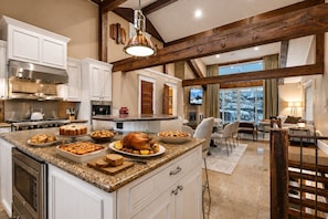 A spacious kitchen with a large island, modern appliances, and a cozy dining area with a view. - 521 Woodside Gem True Ski-in Ski-out On The Gold Coast 3 Bedroom Home (Park City)
