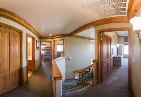 A hallway with wooden doors, a staircase with a wooden railing, and a ceiling vent. - 3 Bedroom Zermatt Villages 773 Condo (Midway)