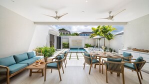 A modern living room with a pool, outdoor seating, ceiling fans, and a view of the neighborhood. - Porters Place 11 3 Bedroom Home (Holetown)