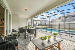 Un espace patio avec une piscine, des sièges d’extérieur et des plantes en pot.