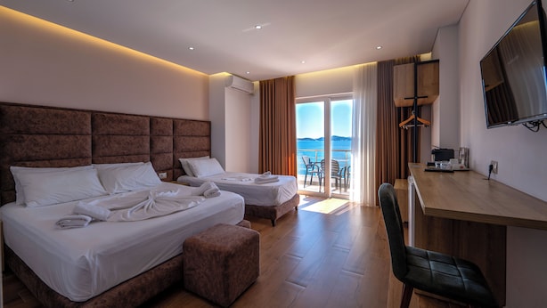 Habitación de hotel con dos camas, un escritorio, una silla y un televisor.