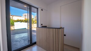 Un interior moderno con un ventanal corredera que da a un balcón, un mostrador de recepción de madera y un suelo de baldosas.