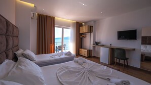 Habitación de hotel con dos camas, un escritorio, una silla, un televisor y vista al mar.