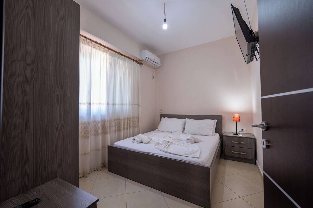 A neatly arranged bedroom with a bed, bedside table, and a lamp.
