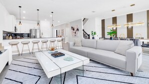 Una cocina moderna con armarios blancos, una isla central e iluminación colgante.