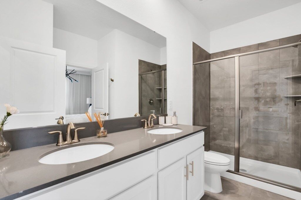A modern bathroom with two sinks, a large mirror, and a glass-enclosed shower.