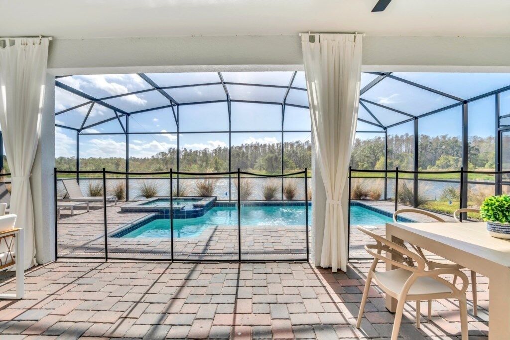 A covered outdoor area with a pool, patio furniture, and a view of a natural landscape.