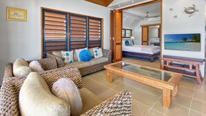 A spacious living area with a sofa, coffee table, and a television. - Pure Magnetic Villa 10 (Nelly Bay)