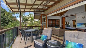 A covered outdoor area with a dining table, chairs, and sofas. - Pure Magnetic Villa 10 (Nelly Bay)