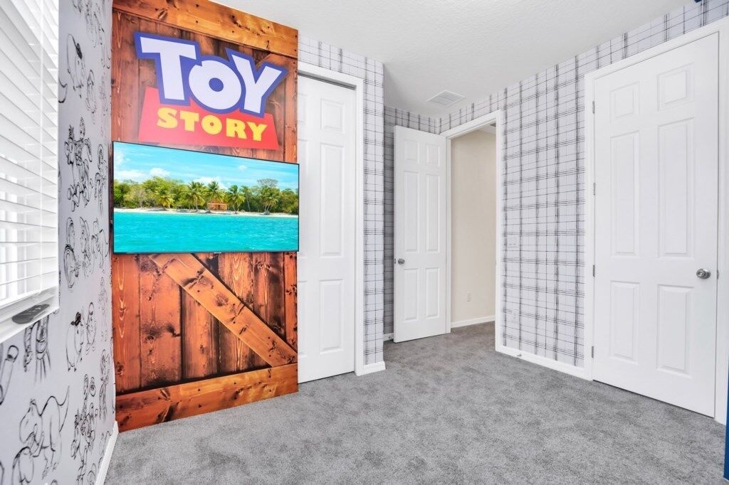 A hallway with a wooden wall and a 'Toy Story' sign, white doors, and a grey carpet.