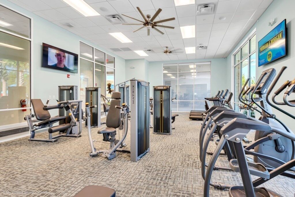 A gym with exercise equipment, a ceiling fan, and a television on the wall.