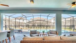 A covered outdoor seating area with wicker furniture, a pool, and a view of the surrounding neighborhood. - 3516laven 8 Bedroom Villa (Davenport)