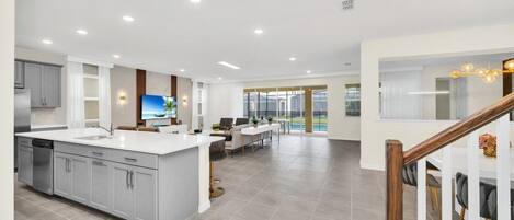 A spacious kitchen with a central island, a dining area with a view, and a staircase leading to a balcony.