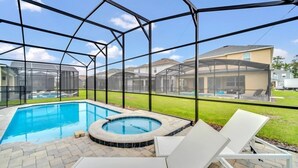 Ein Garten mit Schwimmbad, Whirlpool und Liegestühlen.
