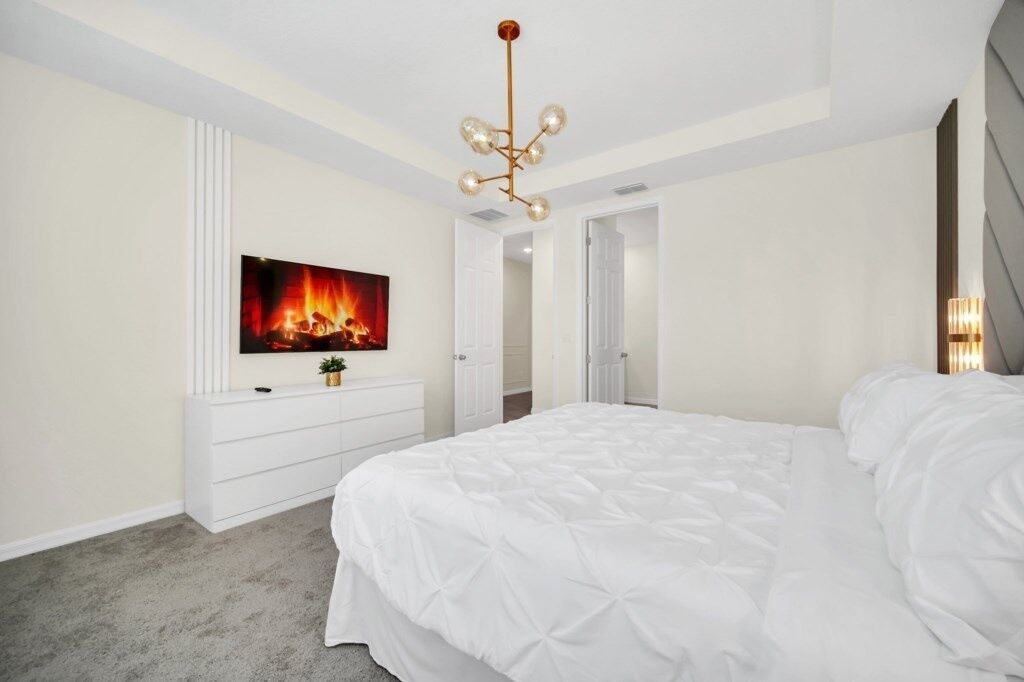 Camera da letto con un grande letto, una televisione a parete e un lampadario.