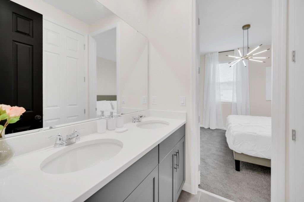 A modern bathroom with two sinks, a large mirror, and a ceiling light fixture.
