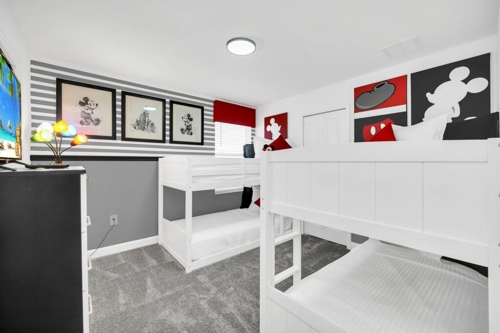Une chambre d’enfant avec des lits superposés, un bureau et des décorations murales.