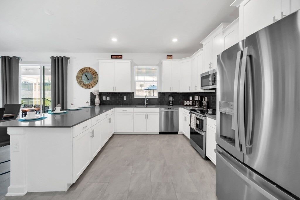 A modern kitchen with white cabinets, stainless steel appliances, and a large island.